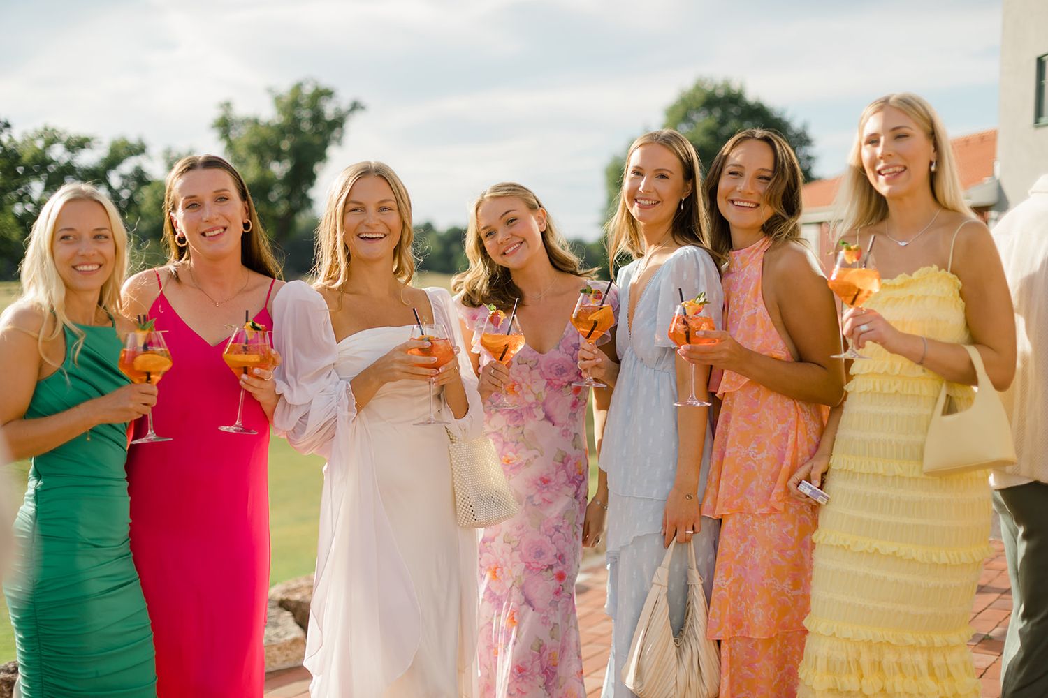 Group of people in colorful dresses standing together outdoors in a celebratory gathering.