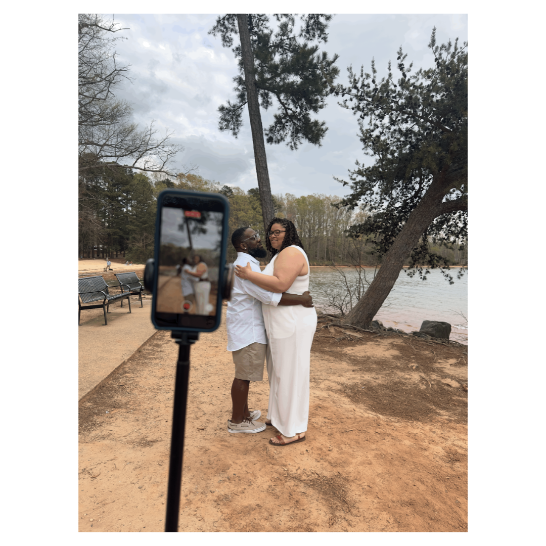 A couple recording content on a phone mounted to a tripod by a lakeside path.