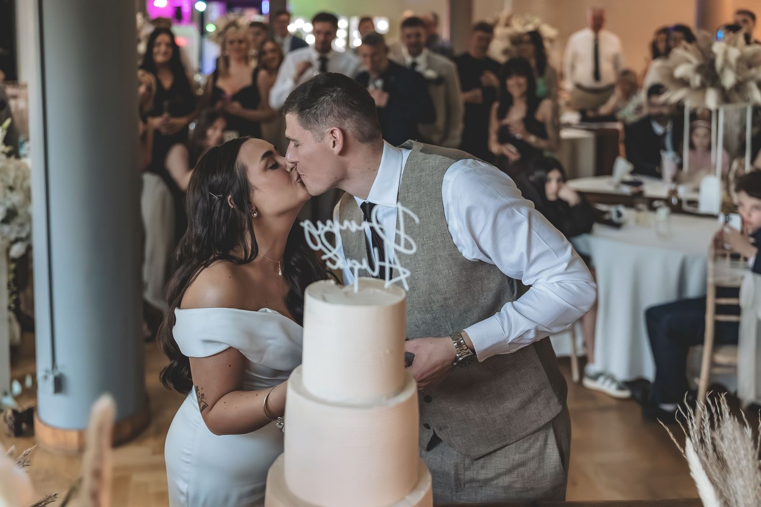 A natural documented photo of bride and groom sharing a kiss during cake cutting.
