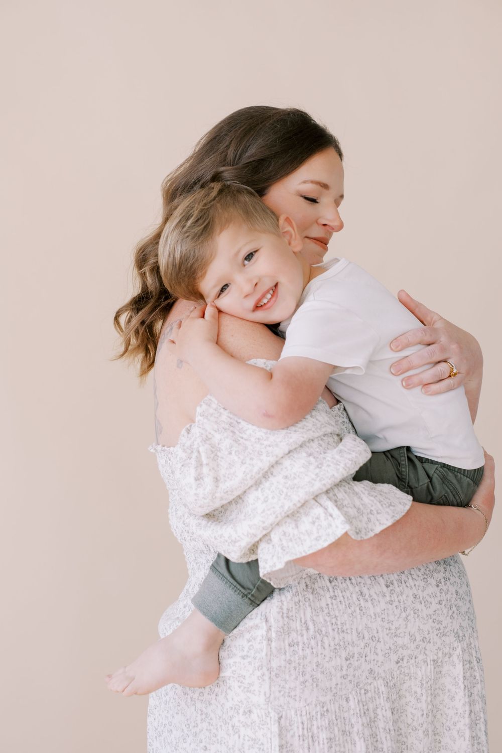 A series of tender embrace photos showing a mother and child in white and grey tones against a neutral backdrop.