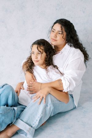 Person in casual white top and distressed jeans poses playfully on light gray background in three connected photos.