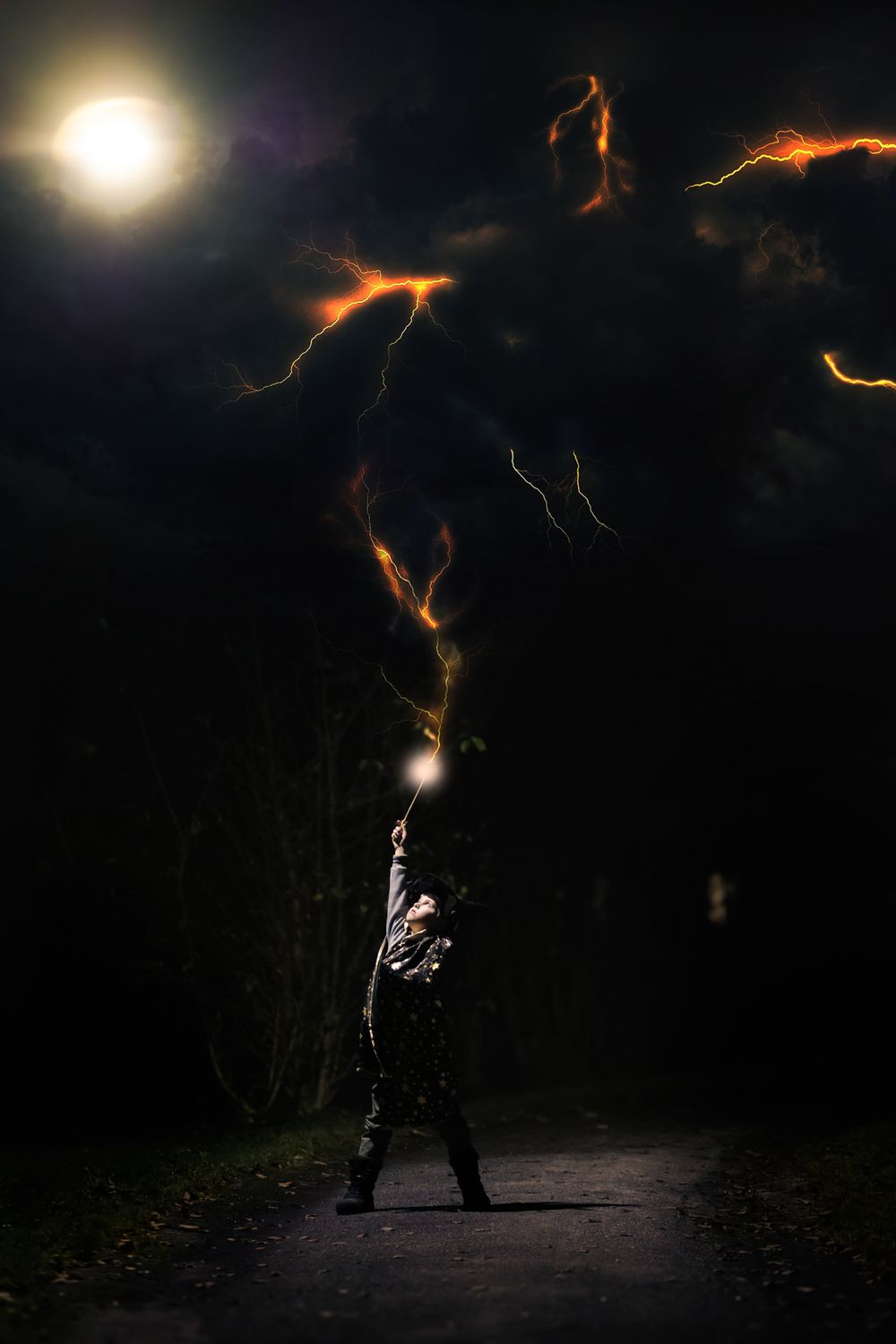 A person performs light painting with fire in a dark outdoor setting, creating glowing trails against the night sky.
