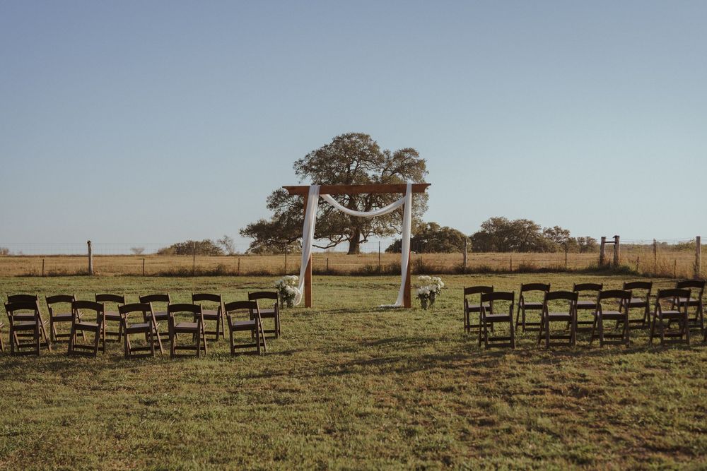 Row of wooden chairs arranged on a grassy hillside under blue sky.