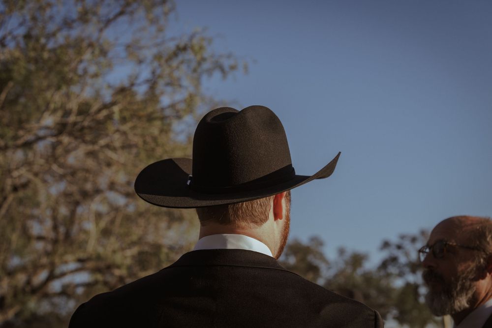 Silhouettes of people wearing cowboy hats against a blue sky.