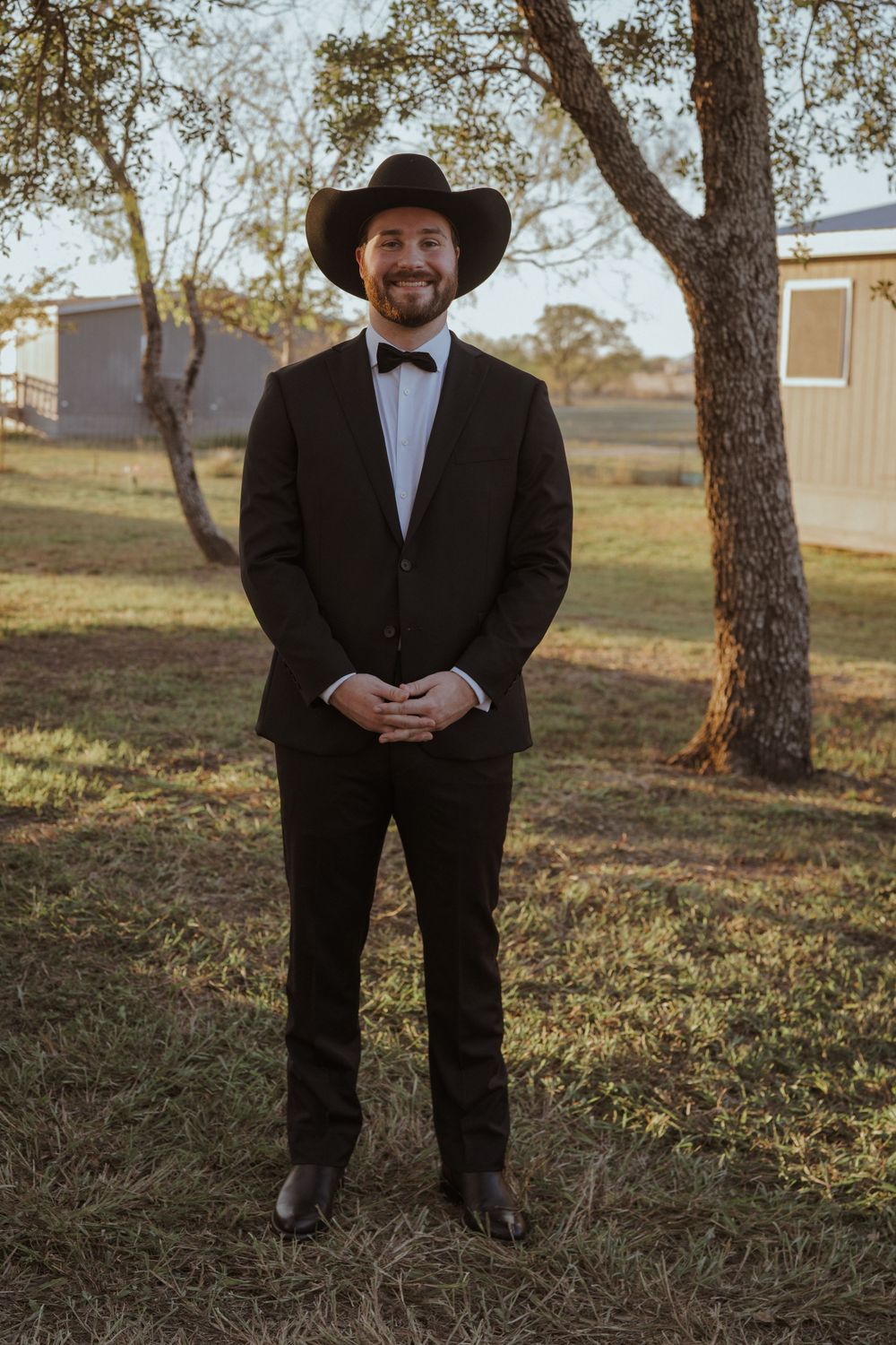 Formal attire and cowboy hat worn at outdoor event.
