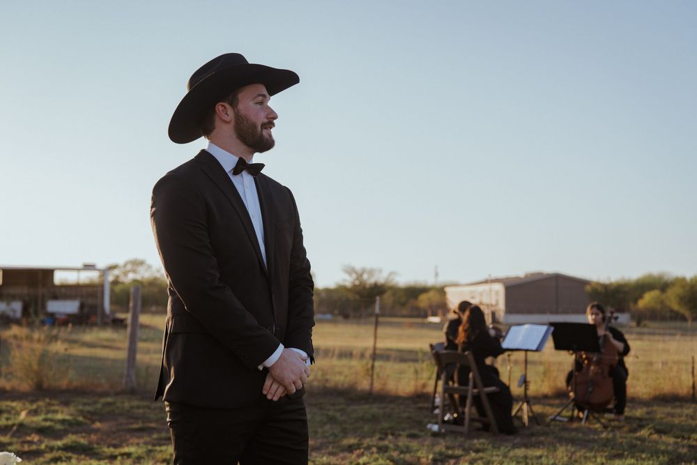 Country wedding ceremony in a rural field with cowboy-themed attire and natural lighting.