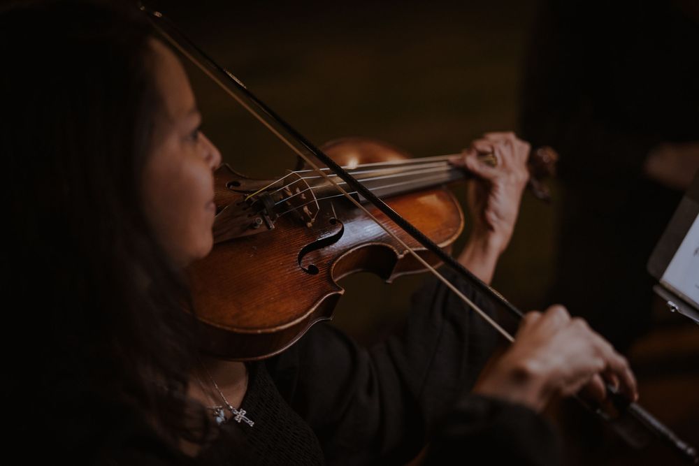 Musicians performing with string instruments in a dark setting.