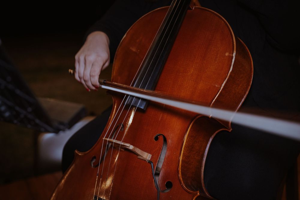 Close-up shots of musicians playing violins and cellos in dramatic lighting.