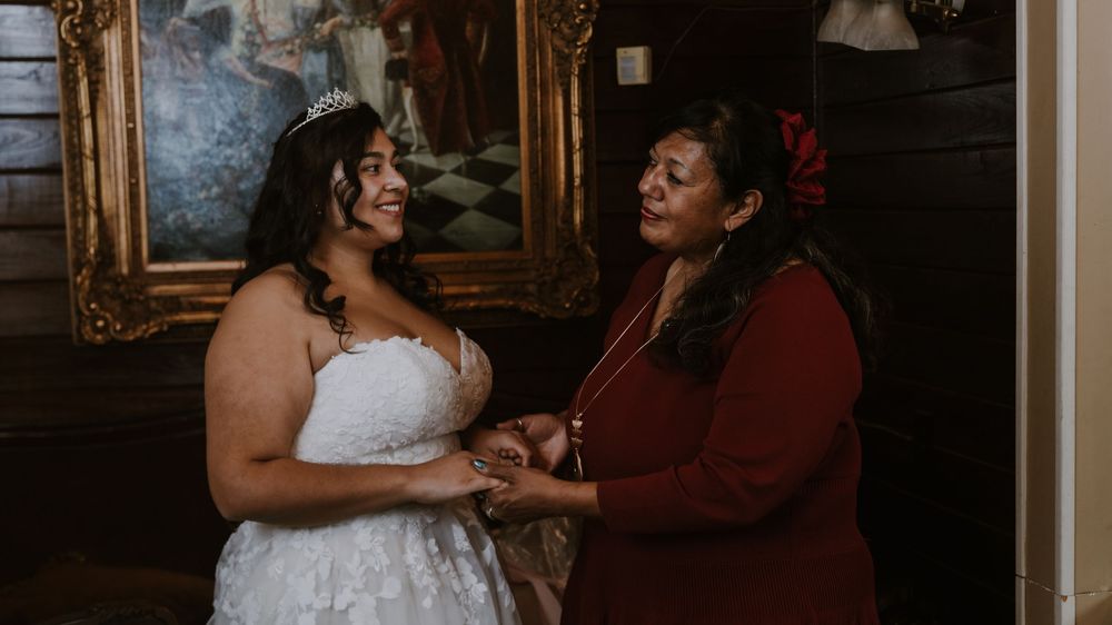 Intimate wedding moment captured in a warmly lit room with ornate gold frames.