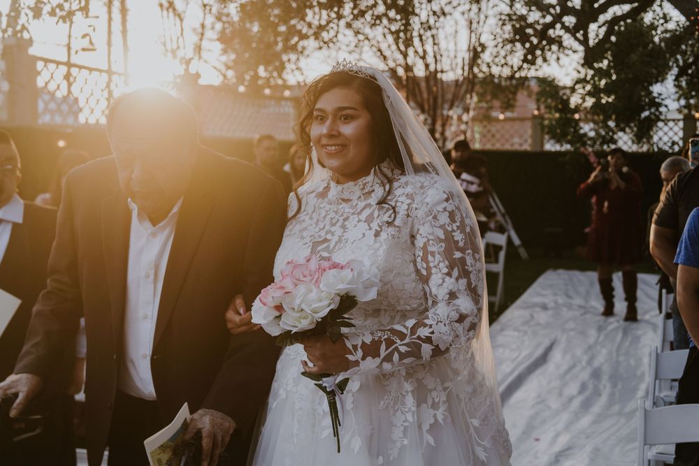 Sunset wedding ceremony with natural backlight filtering through outdoor venue.