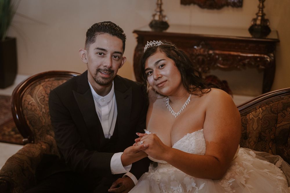 Newlywed couple in formal attire sitting together.