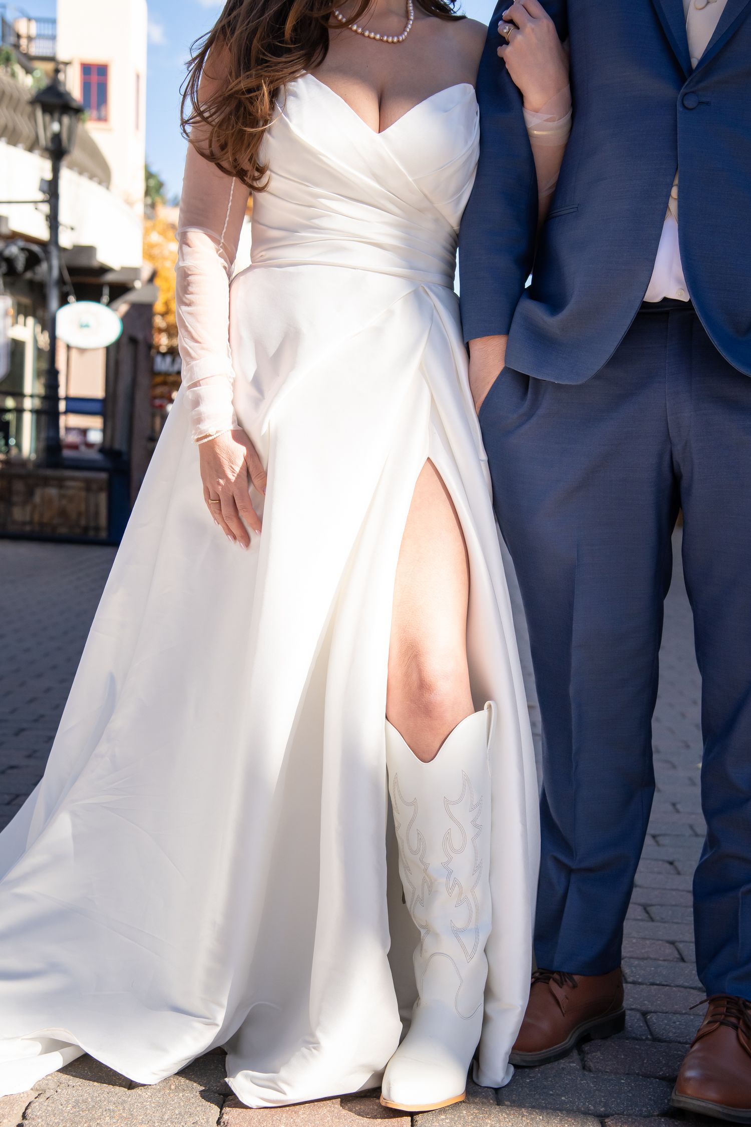 Close-up view of a white wedding dress and cute trendy white cowboy boots as wedding shoes during wedding photos in Vail Colorado