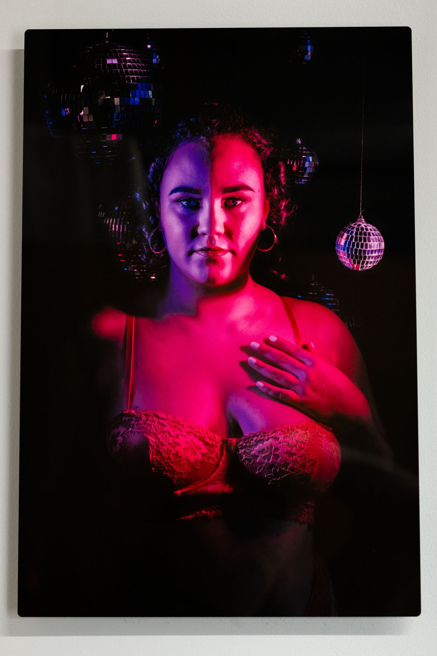 Dramatic portrait with red and blue lighting against dark background featuring disco balls and glowing effects.