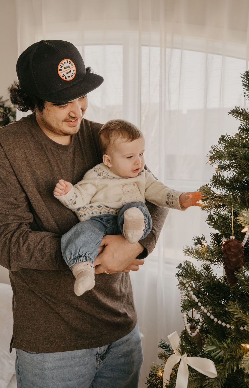 A cozy scene with a baby and parent near a decorated Christmas tree.