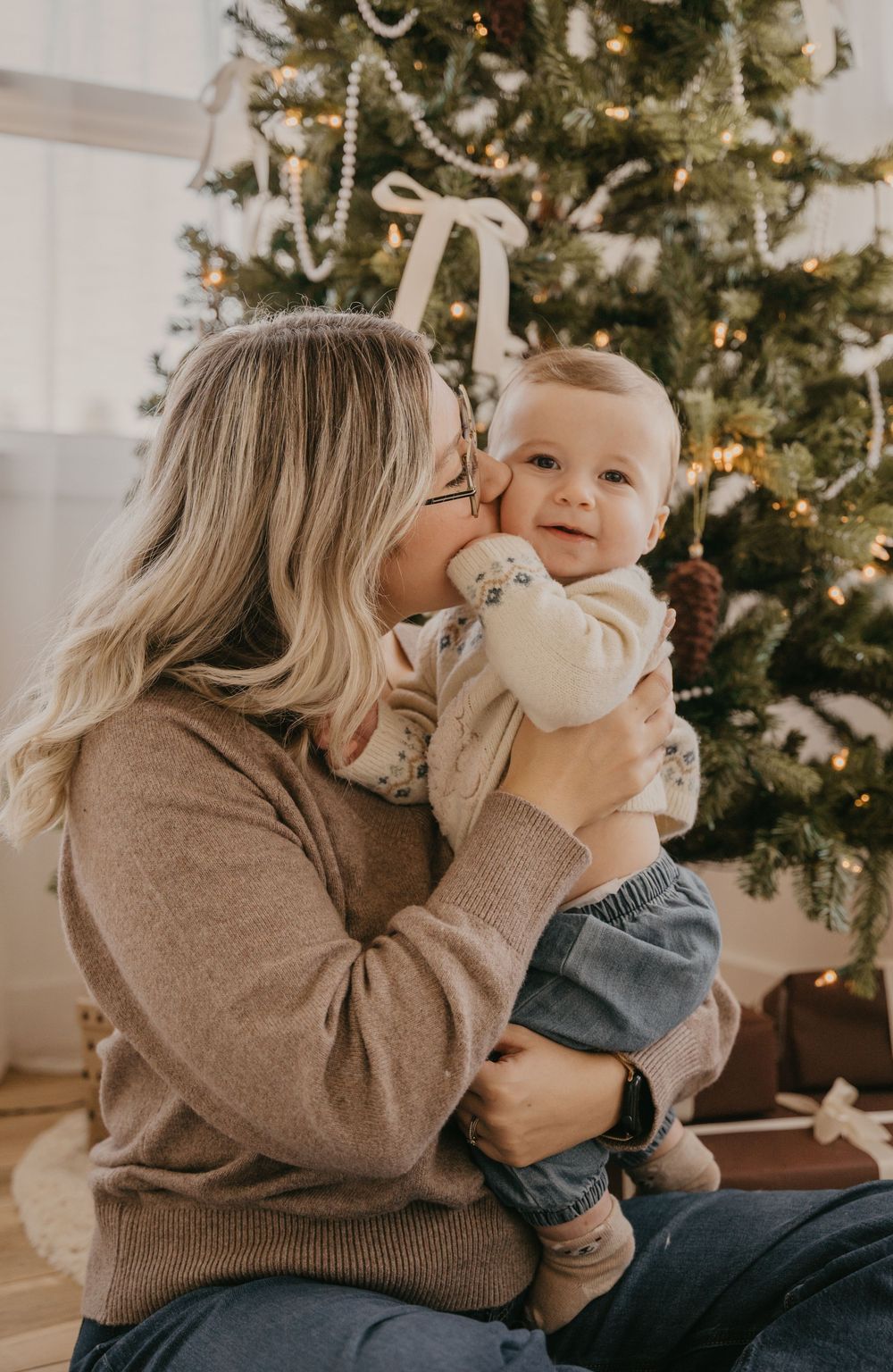 Tender holiday moments shared between parent and baby by a Christmas tree.