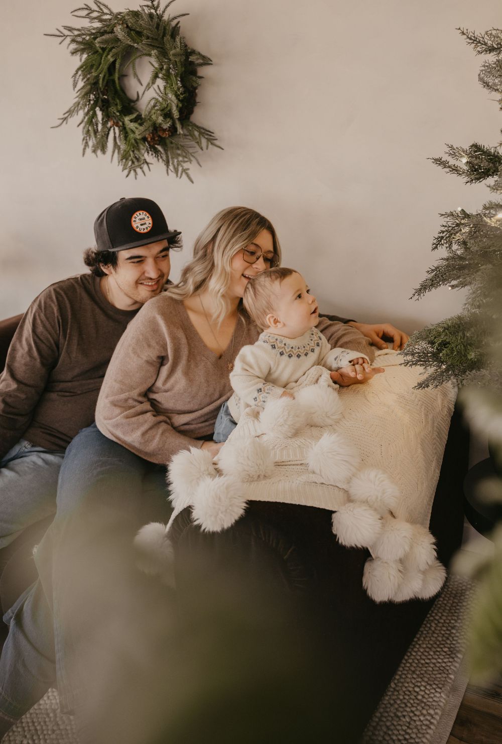 A cozy family moment on the couch during Christmas with evergreen decor and a wreath on the wall.