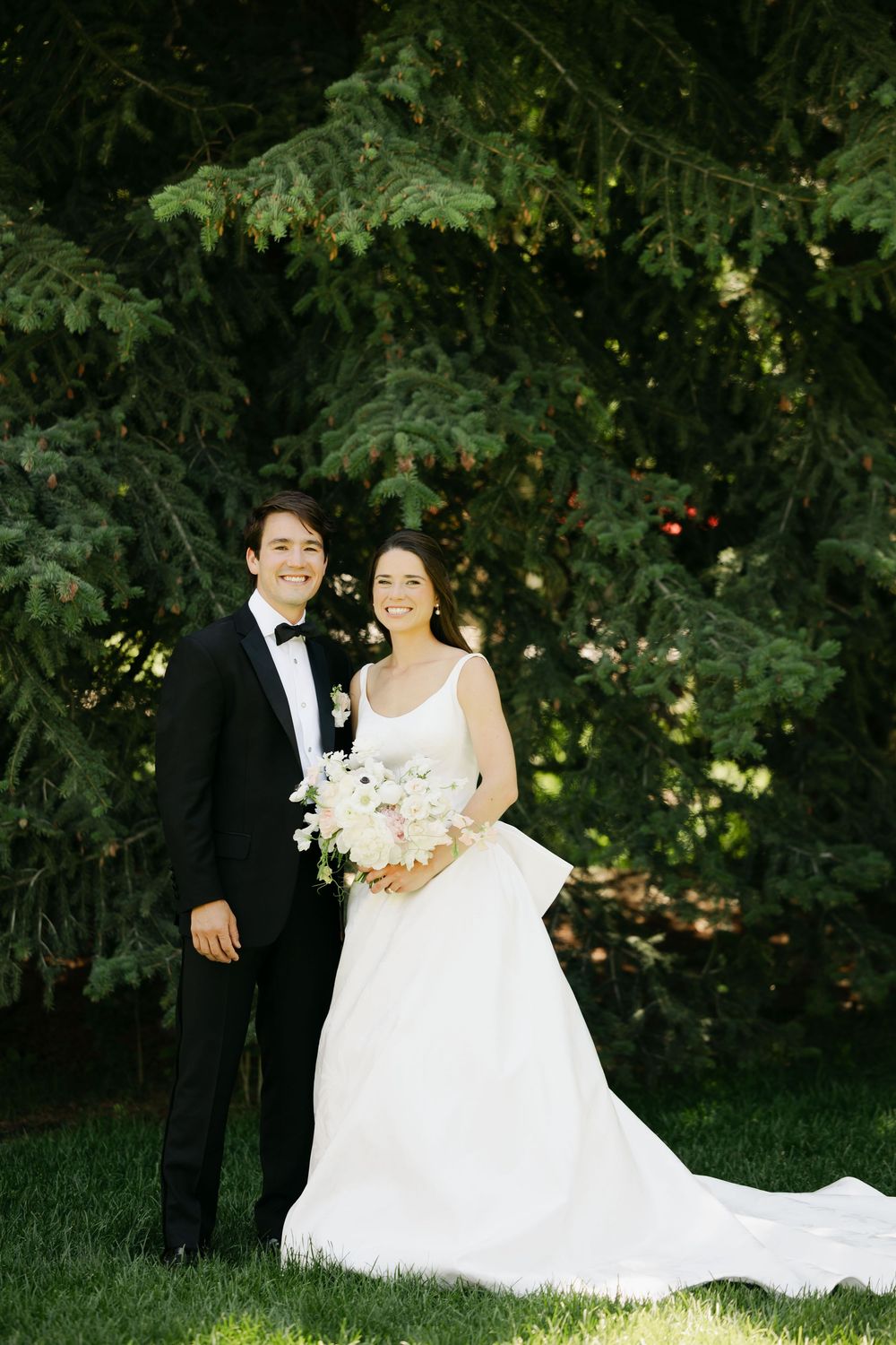A romantic wedding photo shoot in a lush garden setting with a flowing white bridal gown and formal attire.