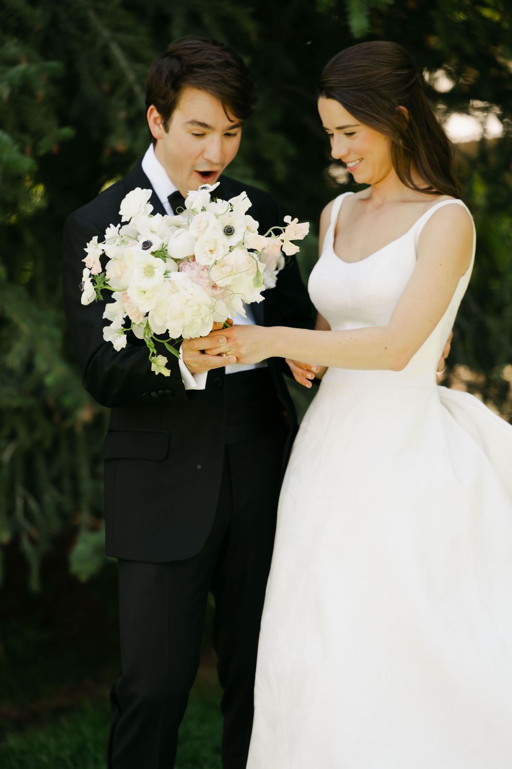 A romantic wedding photo series showing a couple in black and white attire sharing tender moments with white flowers.