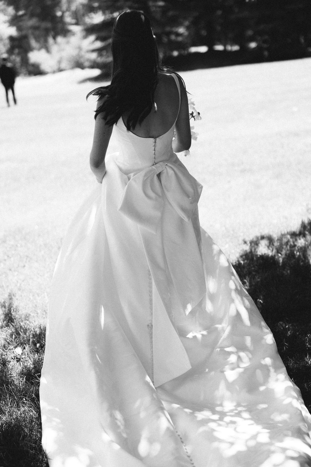 Black and white photo of flowing white wedding dress skirt with dappled sunlight.