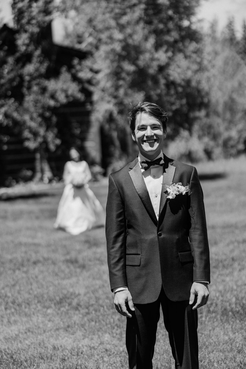Wedding party members in formal attire standing together on grassy lawn.
