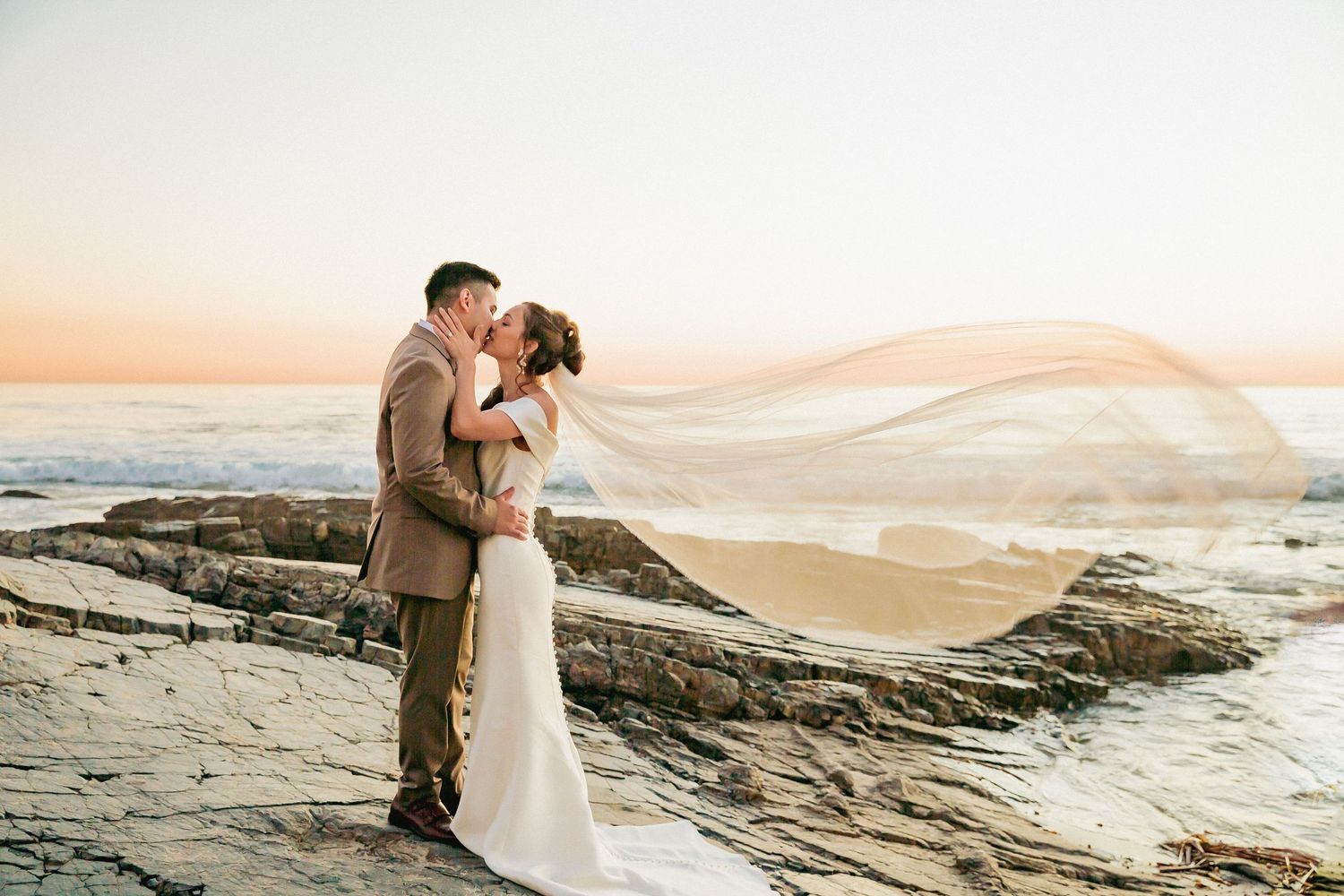 Newlywed couple shares romantic moments in a desert landscape during golden hour sunset photography session.