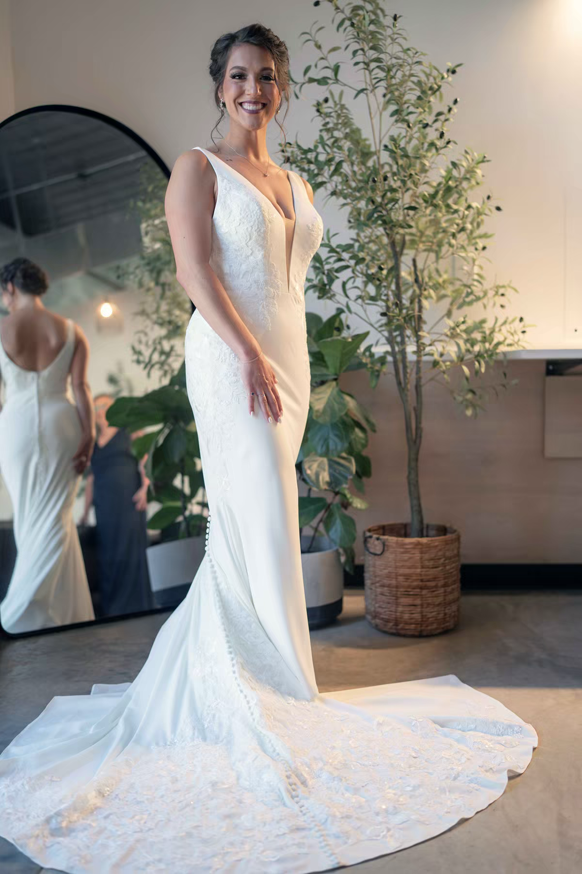 A wedding dress with delicate lace details and flowing train is showcased in a bright bride's room in Retreat 21 Wedding Venue