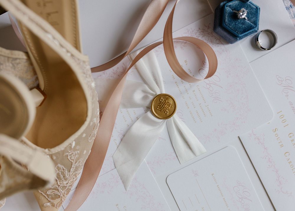 Wedding details featuring cream-colored invitations and vintage-inspired accessories.