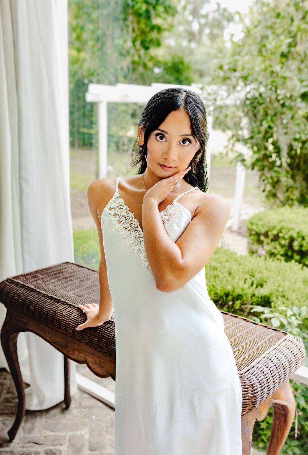 Elegant white dress portrait on wicker furniture outdoors.