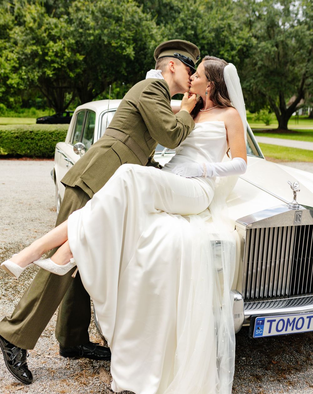 A romantic wedding photo shoot with a vintage white Rolls Royce on a gravel driveway.