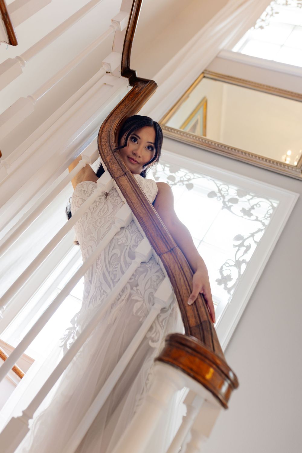 Artistic bridal portraits on a white staircase with natural window lighting.