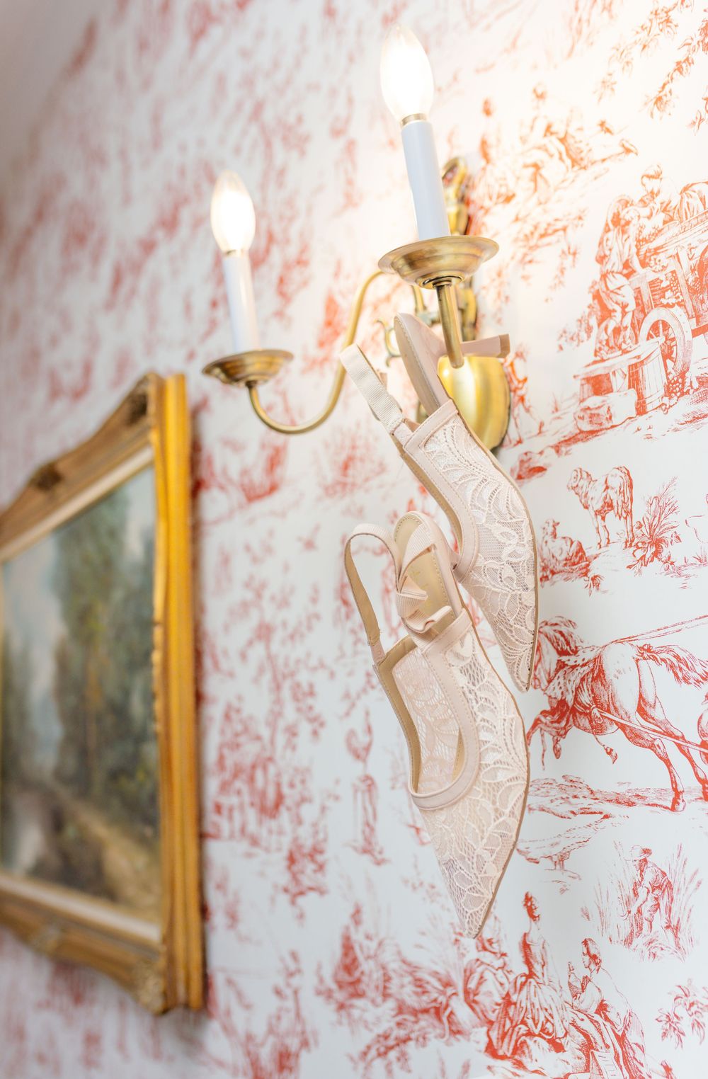 Vintage-style wall sconce against red toile wallpaper in an elegant wedding venue.