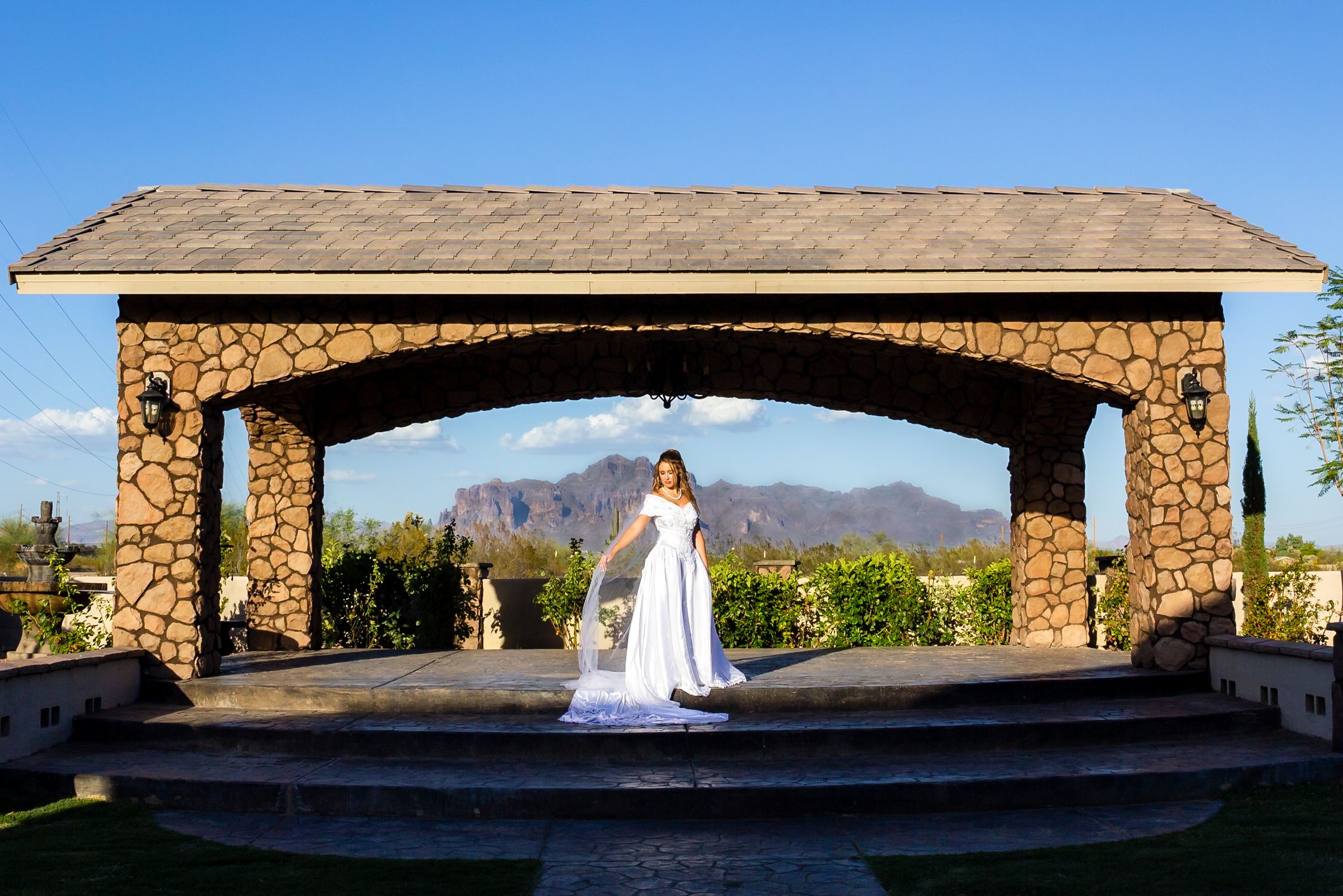 A stone pavilion with a scenic mountain backdrop stands at a desert wedding venue in Arizona.