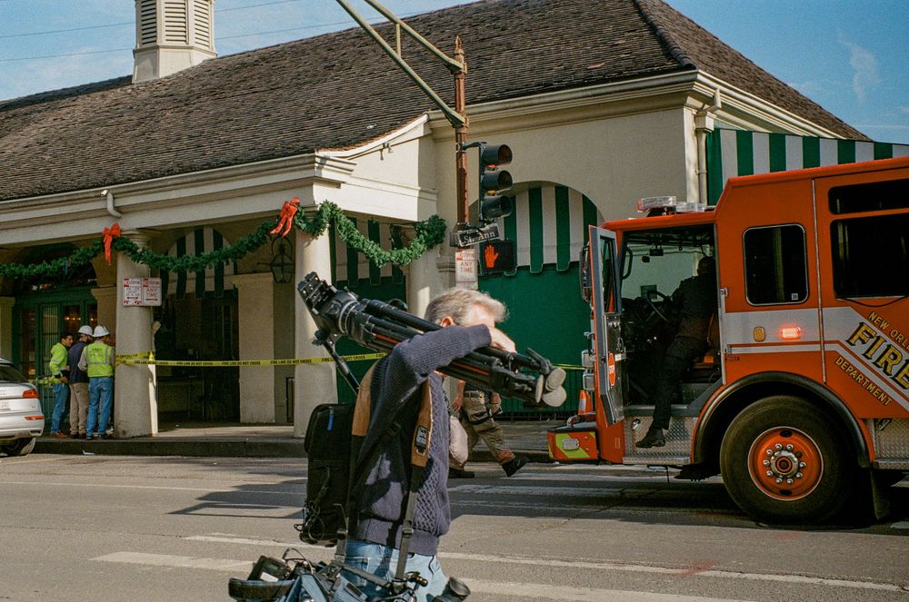 Street performer balancing on equipment near food truck and storefront with green awning.
