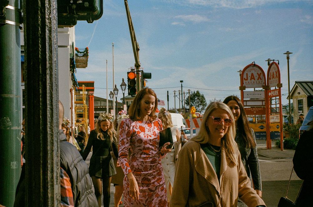 Busy street scene with pedestrians walking past colorful urban buildings.