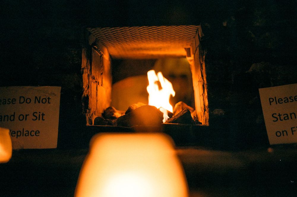Warm glow of fire illuminates dark space with warning signs visible.