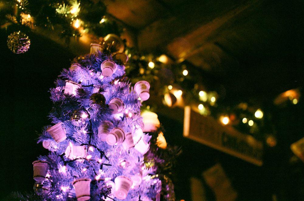 Purple illuminated Christmas tree with twinkling lights glows against a dark background.