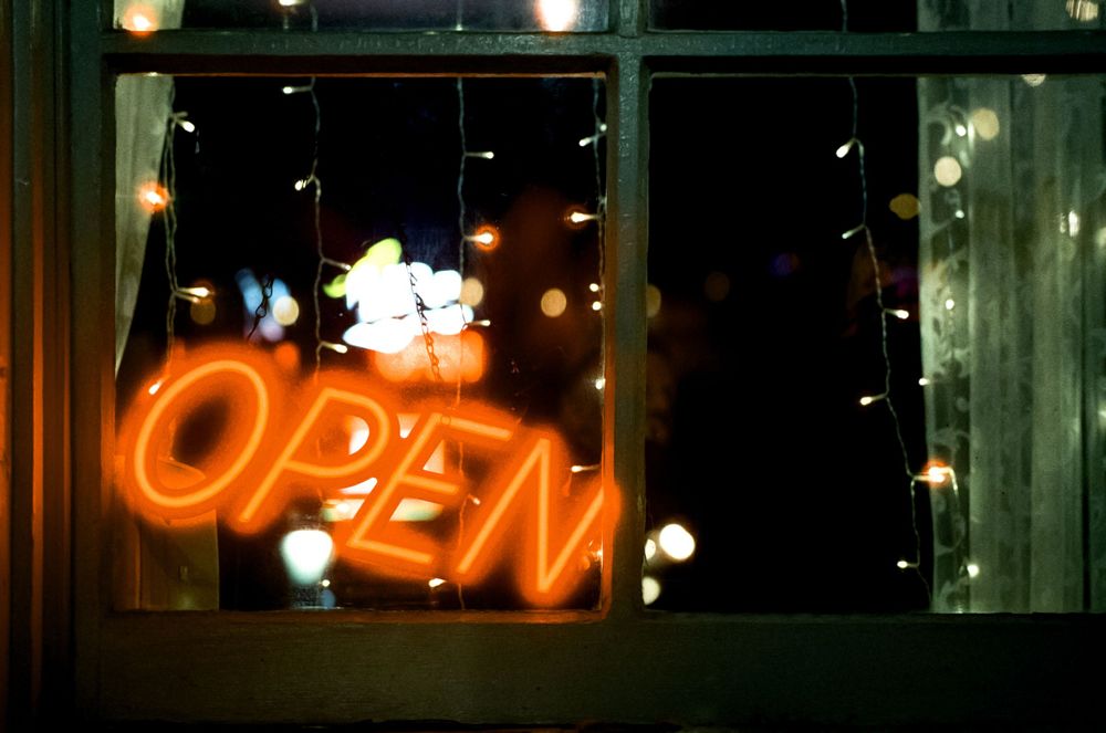 Neon orange OPEN sign glows in a dark window display.
