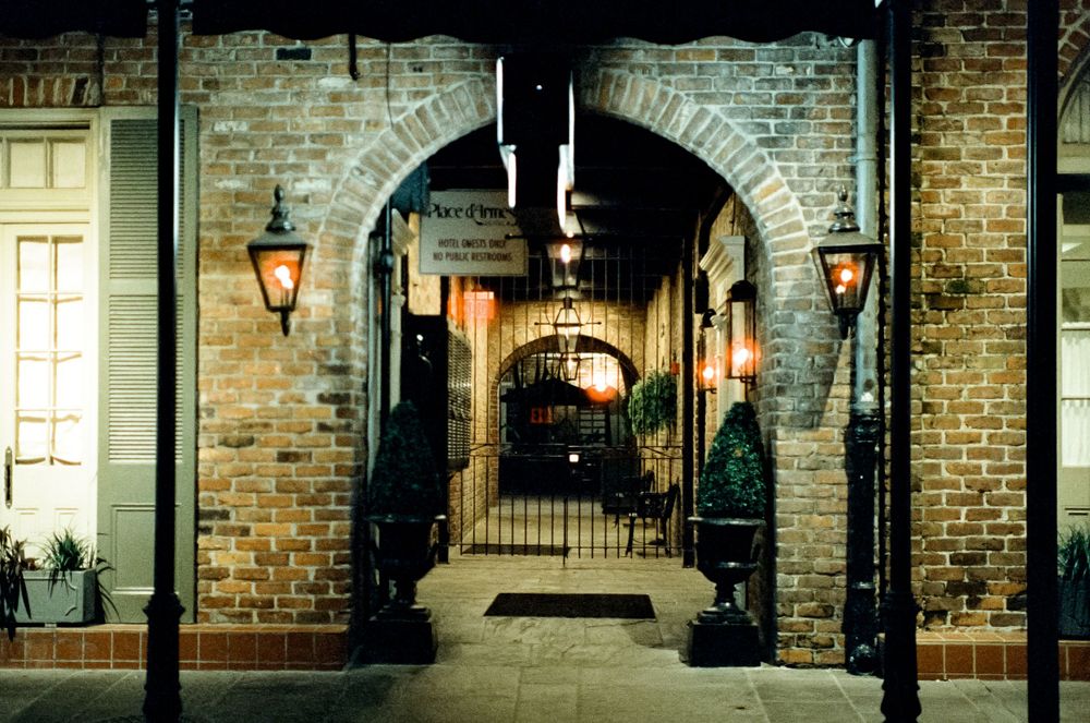 Brick archway with gas lamps leads down a covered passageway.