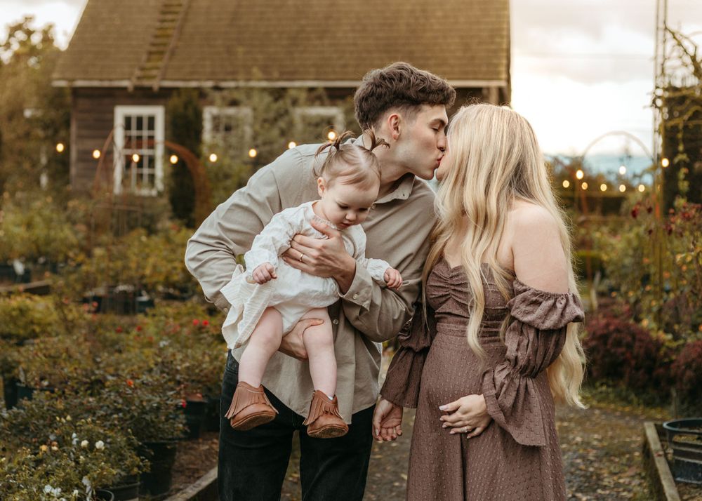 Sweet autumn family moment captured in front of a rustic building with fall foliage.