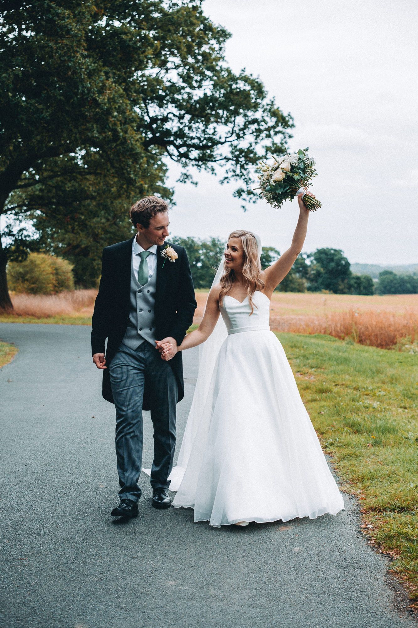 Couple shares intimate moment on country road during autumn wedding.