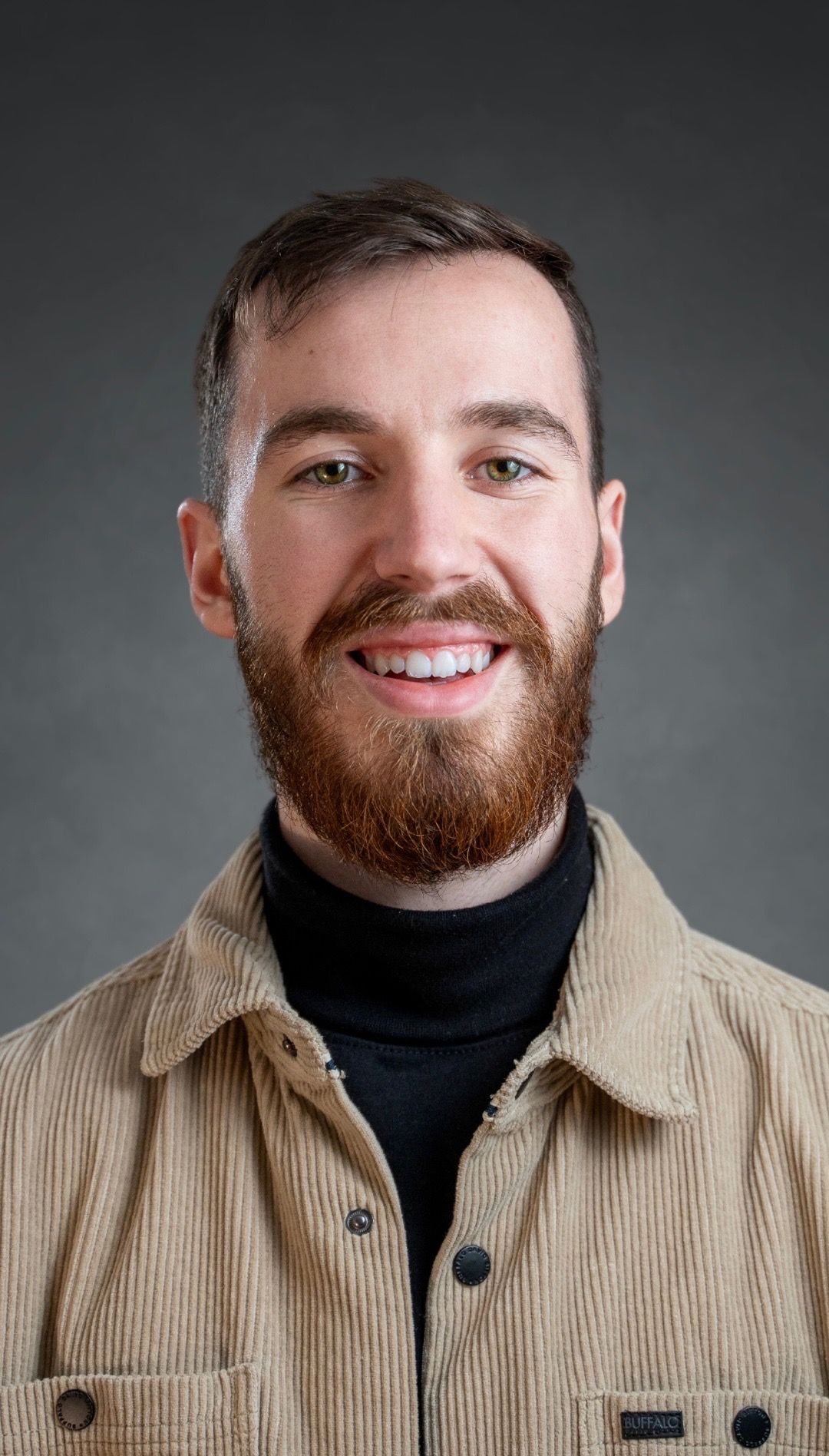 Professional headshot of someone in casual attire against a dark background.