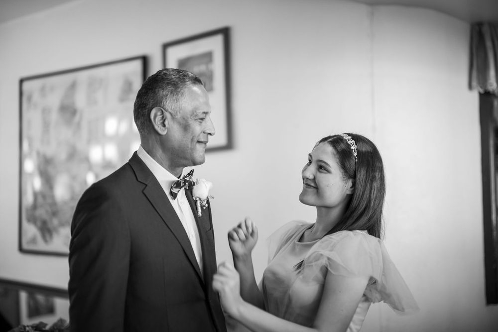 An emotional father-daughter moment is captured in black and white during wedding preparations.