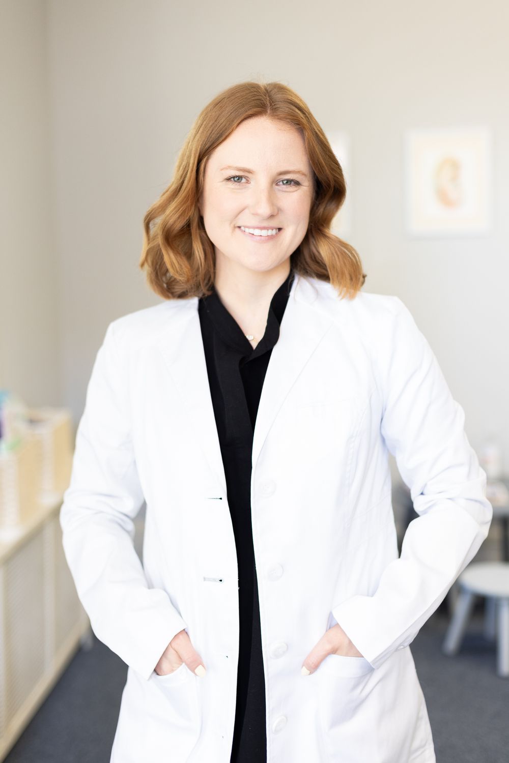 A professional in a white lab coat stands confidently in a medical office setting.