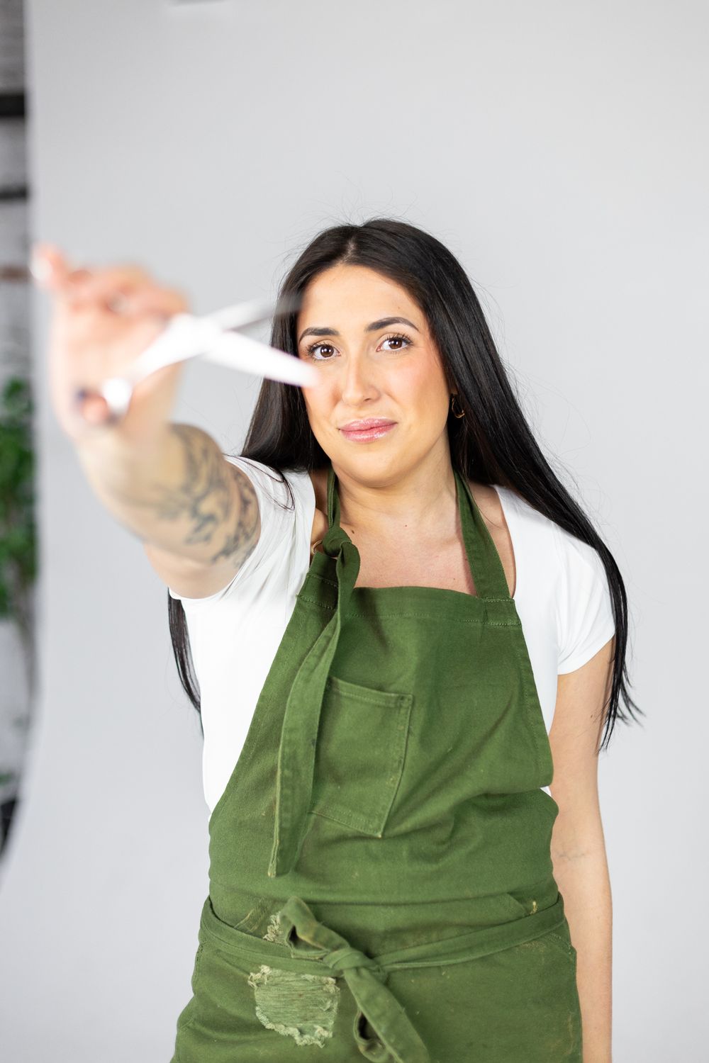 A person in a green apron points towards the camera in a bright indoor setting.