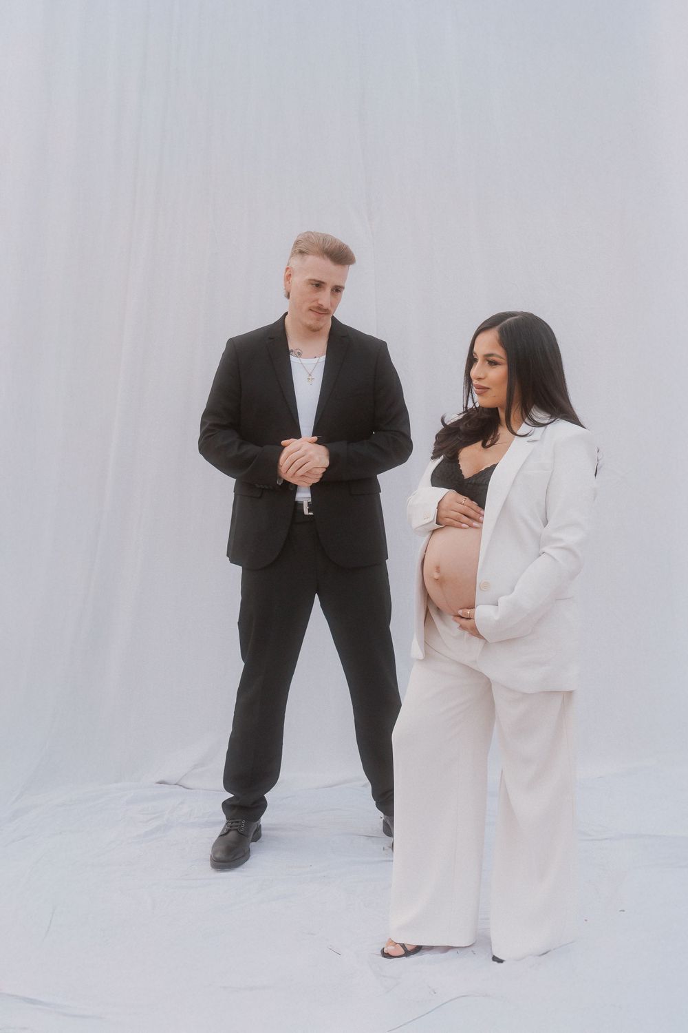 Modern maternity studio portrait with couple in contrasting black and white formal attire.