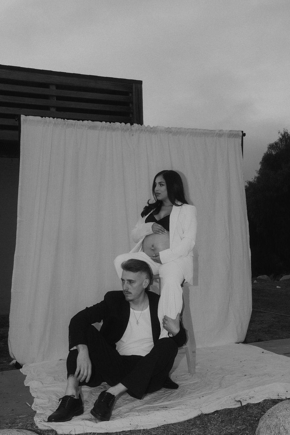 Maternity photoshoot against white backdrop with couple in contrasting black and white outfits.