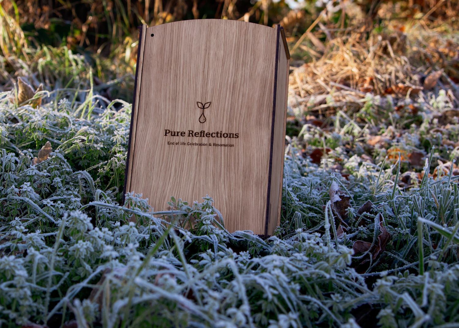 Wooden branded box displayed over frosty grass in natural setting.