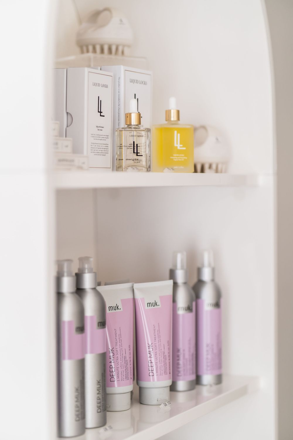 Beauty product shelf displaying skincare bottles and tubes in white and purple packaging.