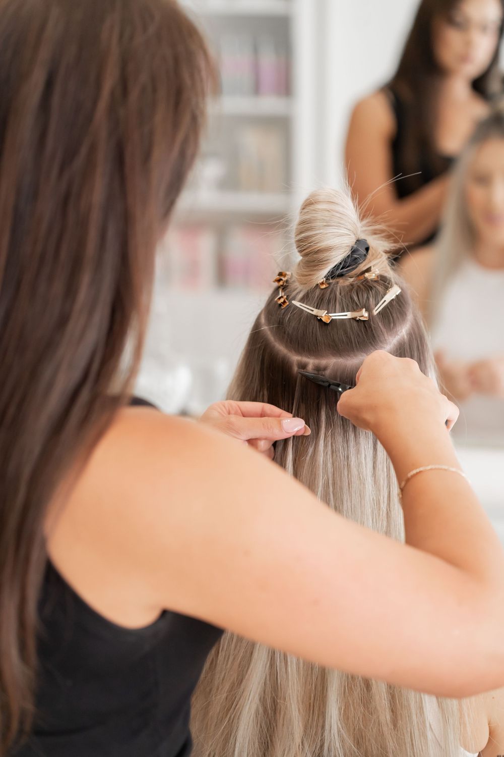 Professional stylist installing hair extensions using sectioning technique.
