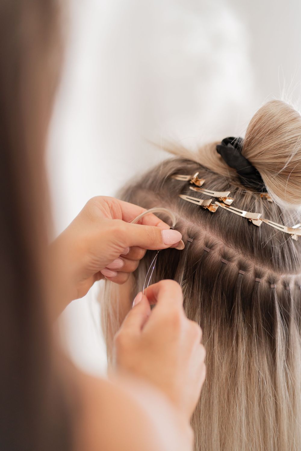 Close-up of hair extension application process showing clips and sectioning.
